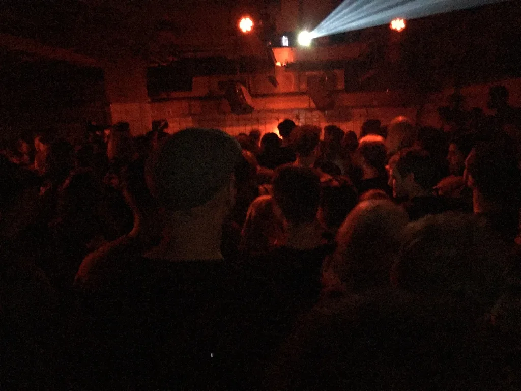 A theater audience under a red stage light